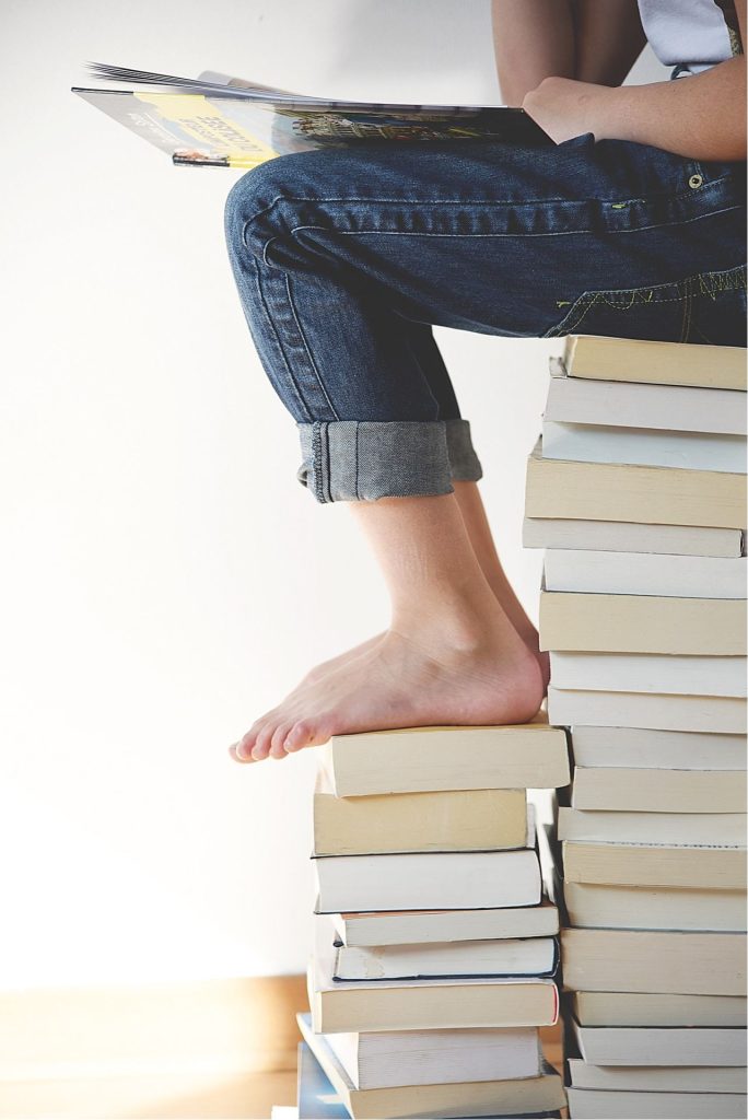 A child sitting on a tall stack of books