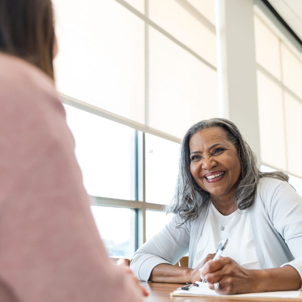 an adult student happily sitting with her reading tutor