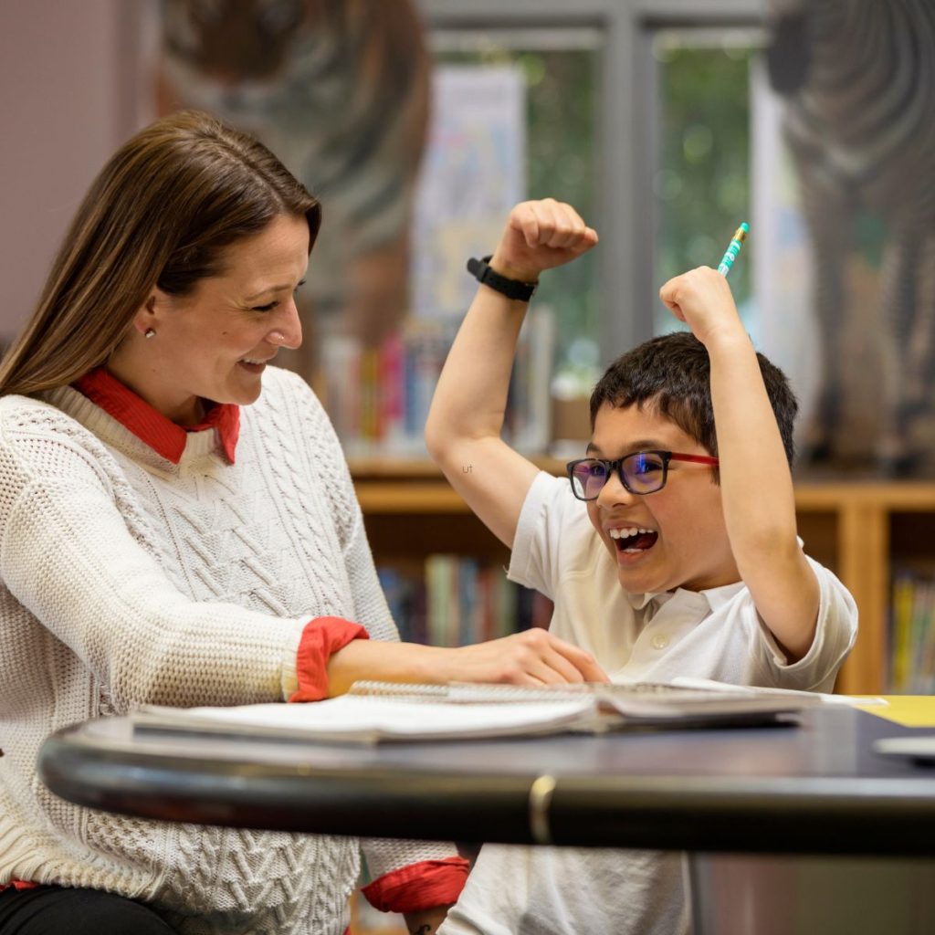 reading tutor sitting near a happy student celebrating reading success